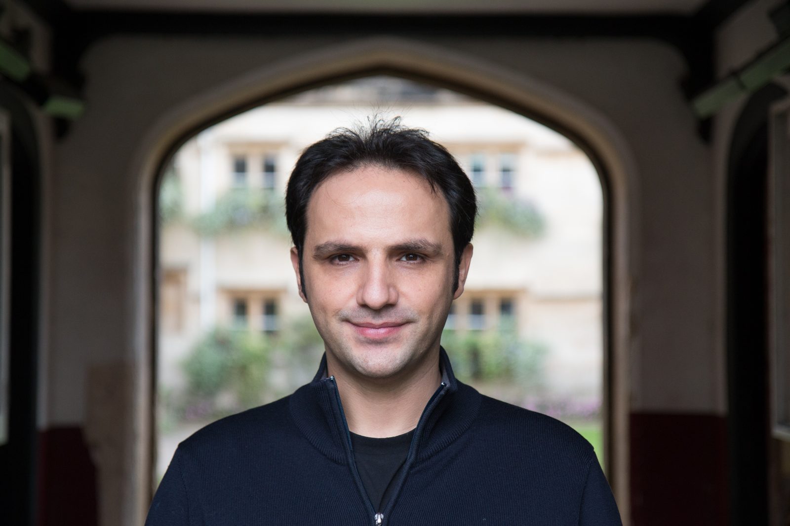 Omer Gunes standing in a stone archway at Pembroke College, Oxford