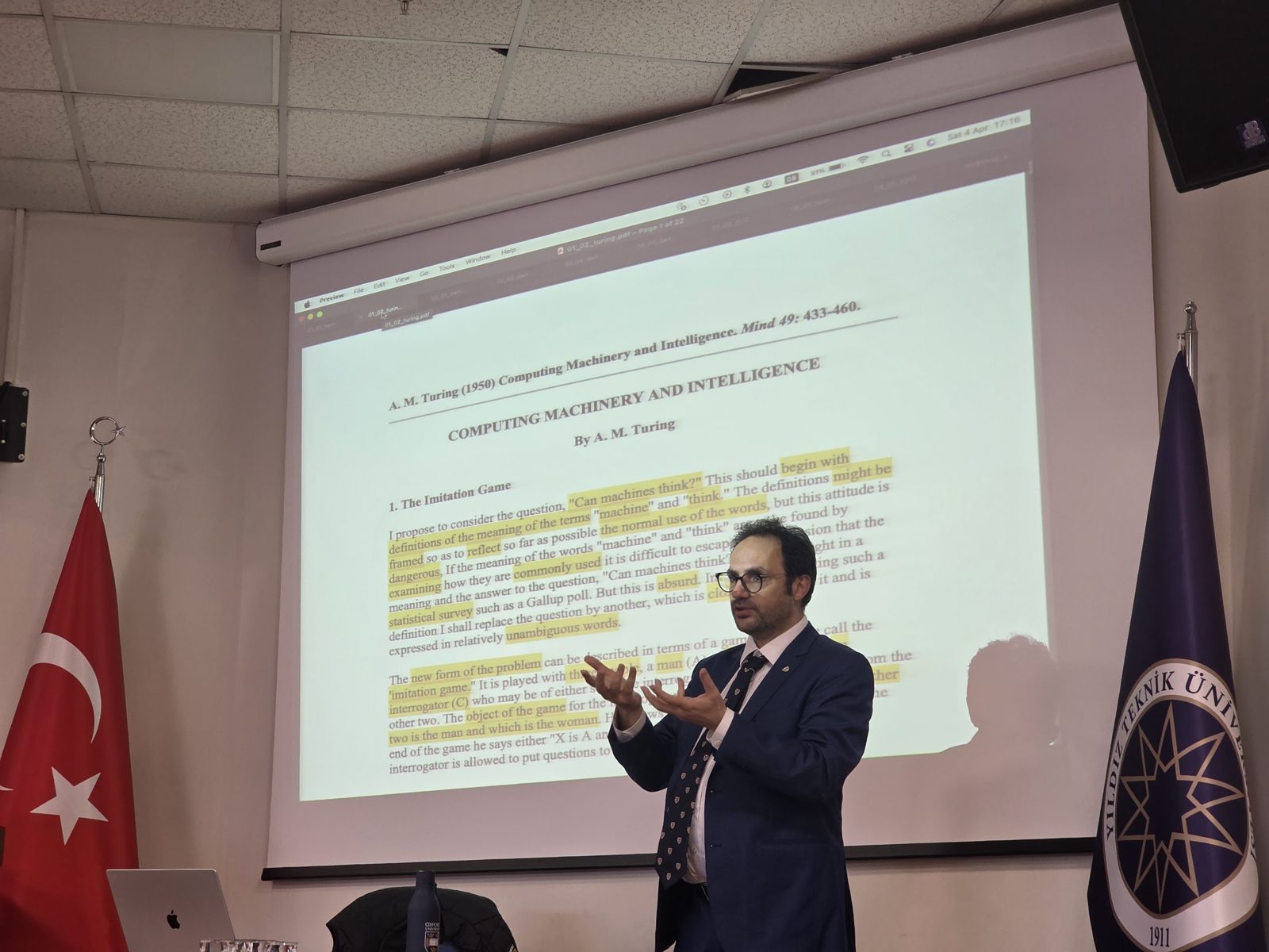 Omer Gunes speaking in front of a slide of Alan Turing's paper Computing Machinery and Intelligence