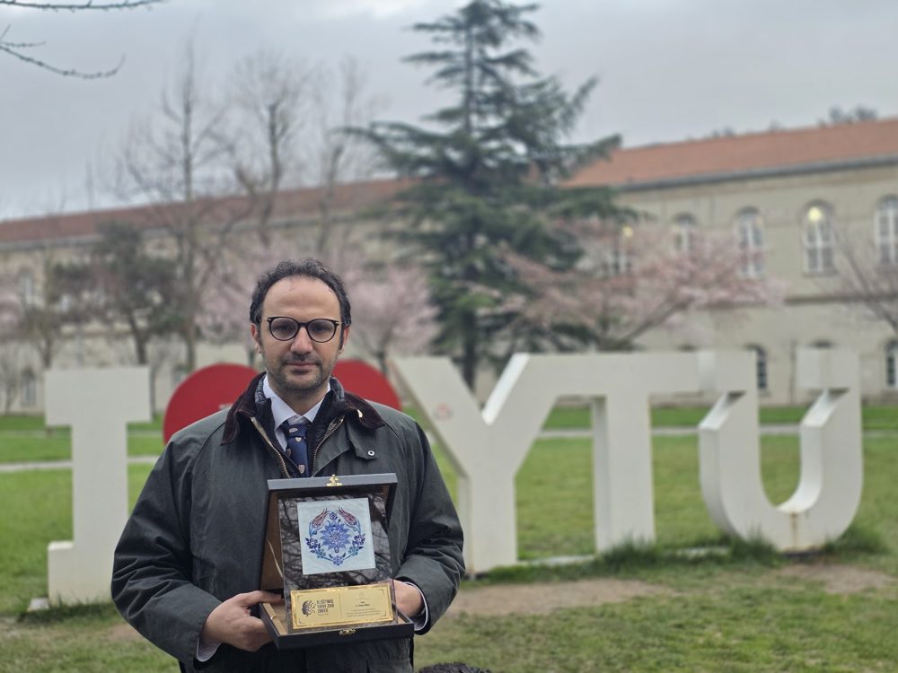 Omer Gunes holding a speaker plaque at Yıldız Technical University